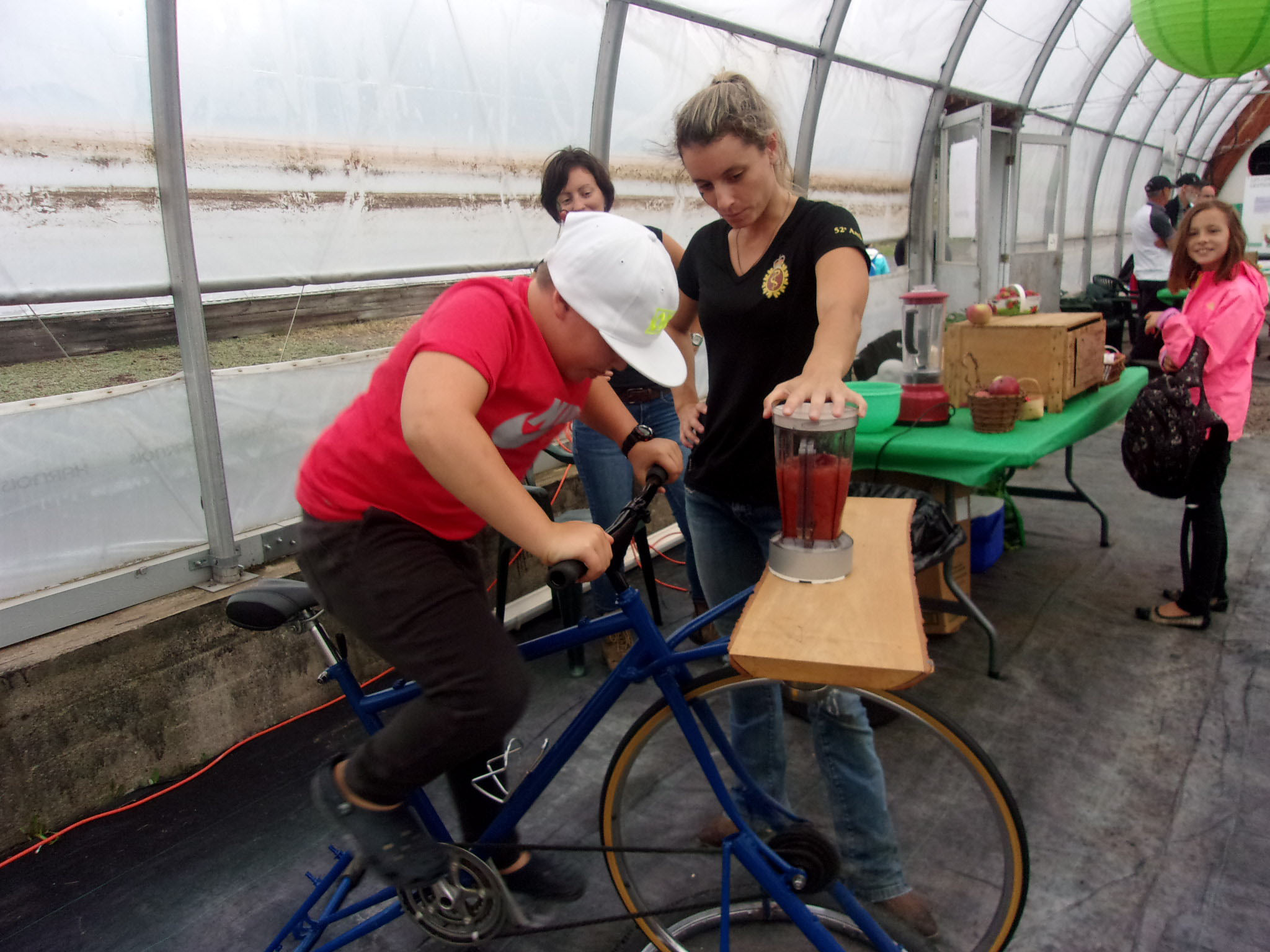 Élisabeth et Marie-Alexandre Gamache avec un volontaire actionnant le "vélo à smoothies". 